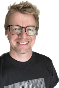 a man with glasses smiling in front of a black background